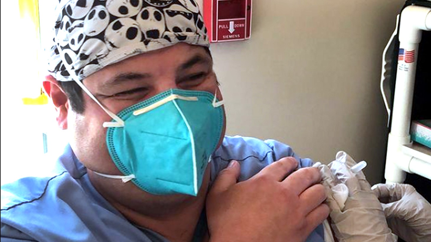 年轻的拉丁裔男人，戴着蓝色面具，接种疫苗
