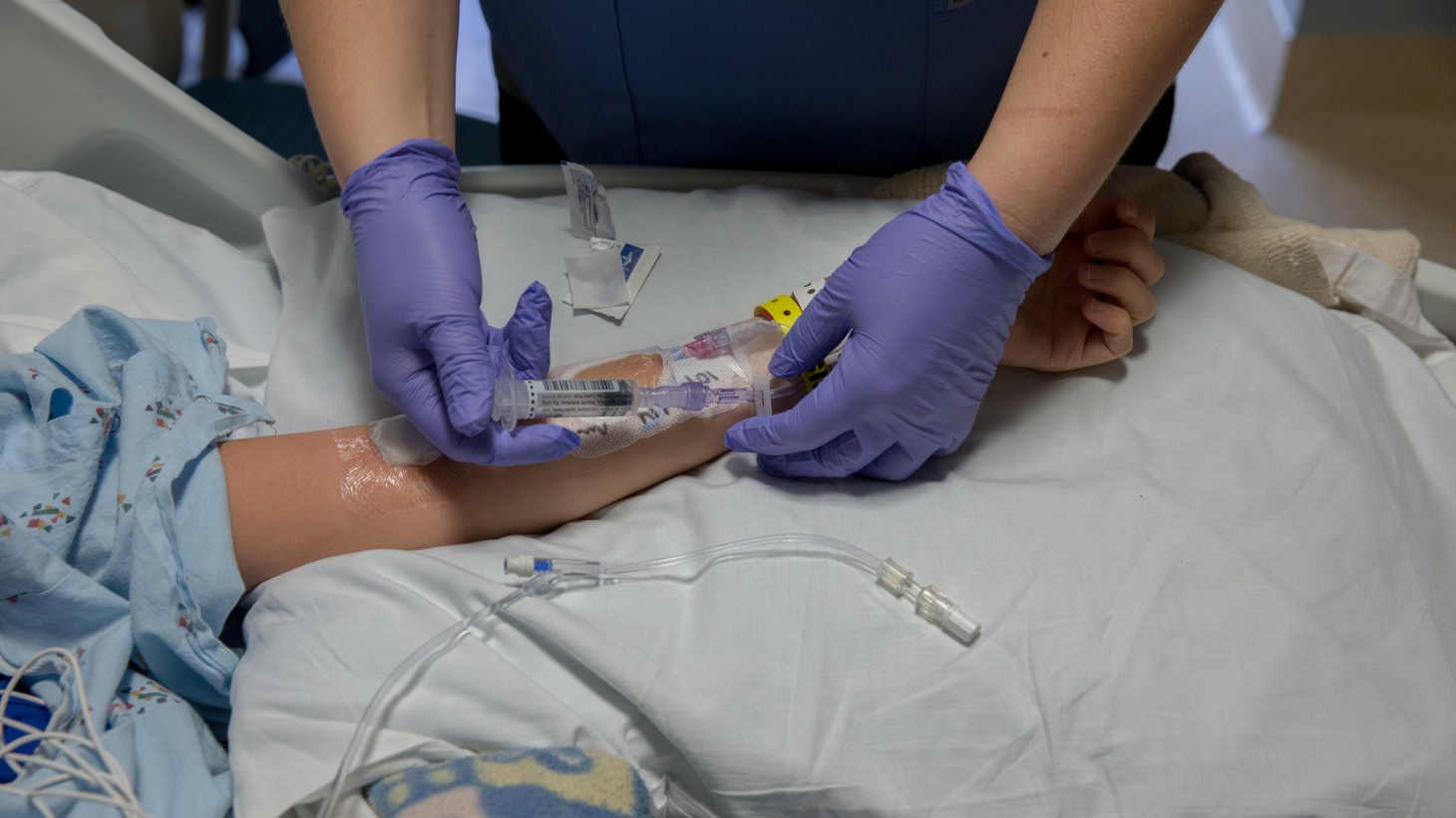 A pair of hands inserting an IV in a patient's arm