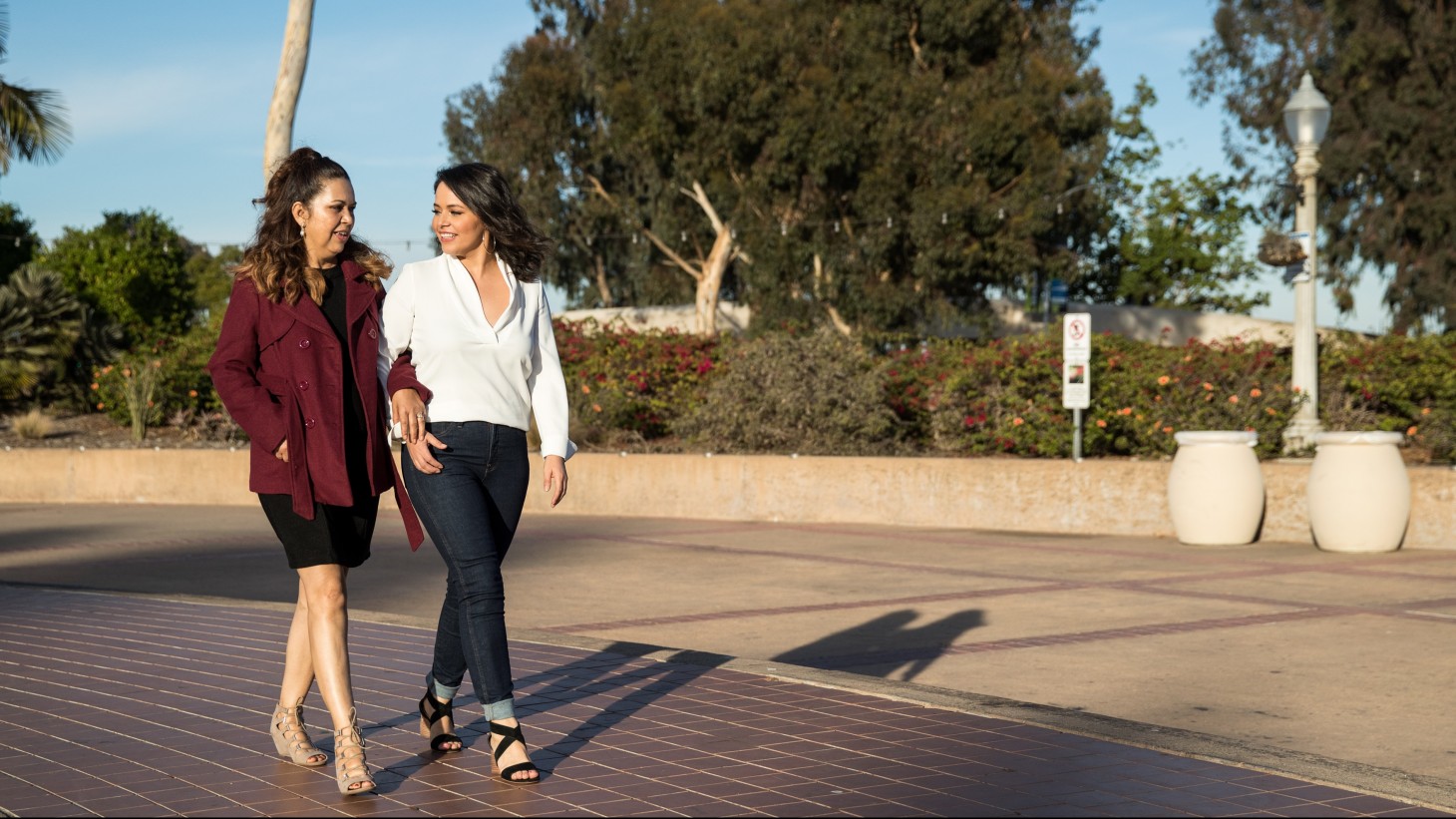 两个女人在阳光明媚的日子里手挽着手散步