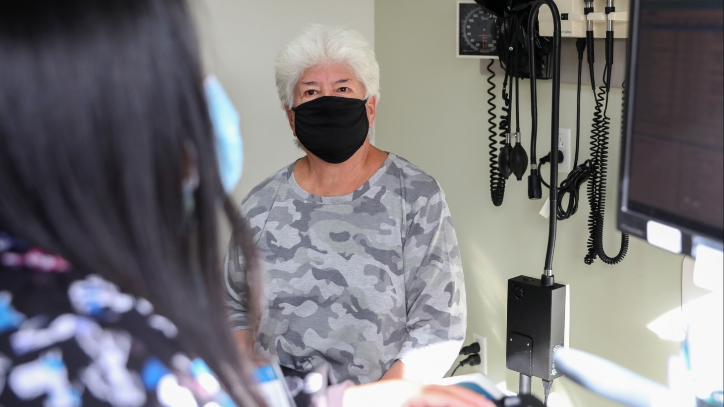 老年女性病人在医生办公室，戴着口罩