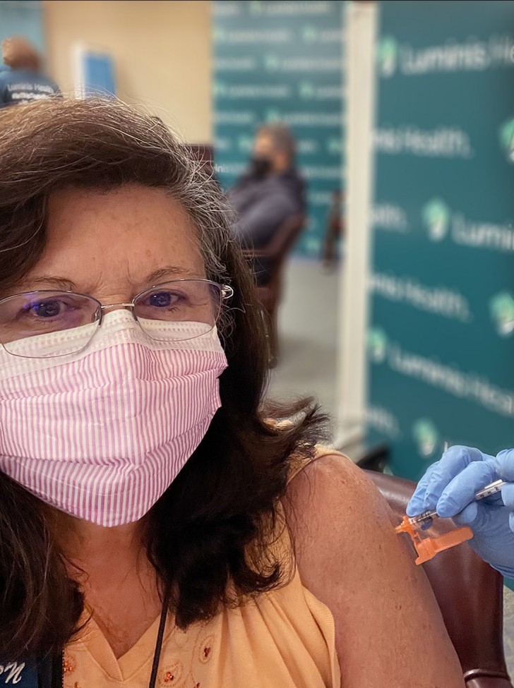 戴眼镜、穿衬衫的棕色头发女性正在接种新冠病毒疫苗。